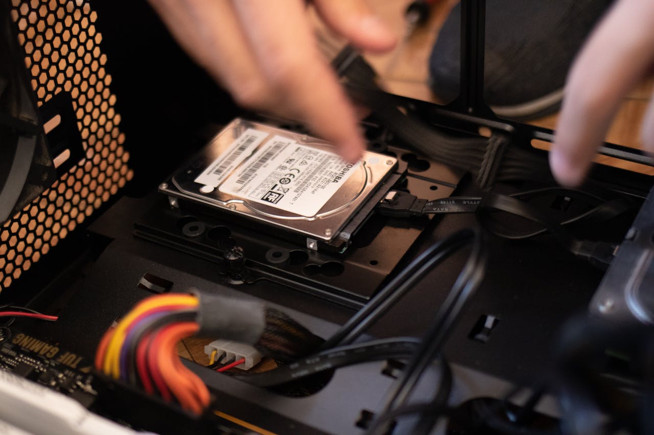 Hands installing a hard drive in a computer case, emphasizing technology and connectivity.